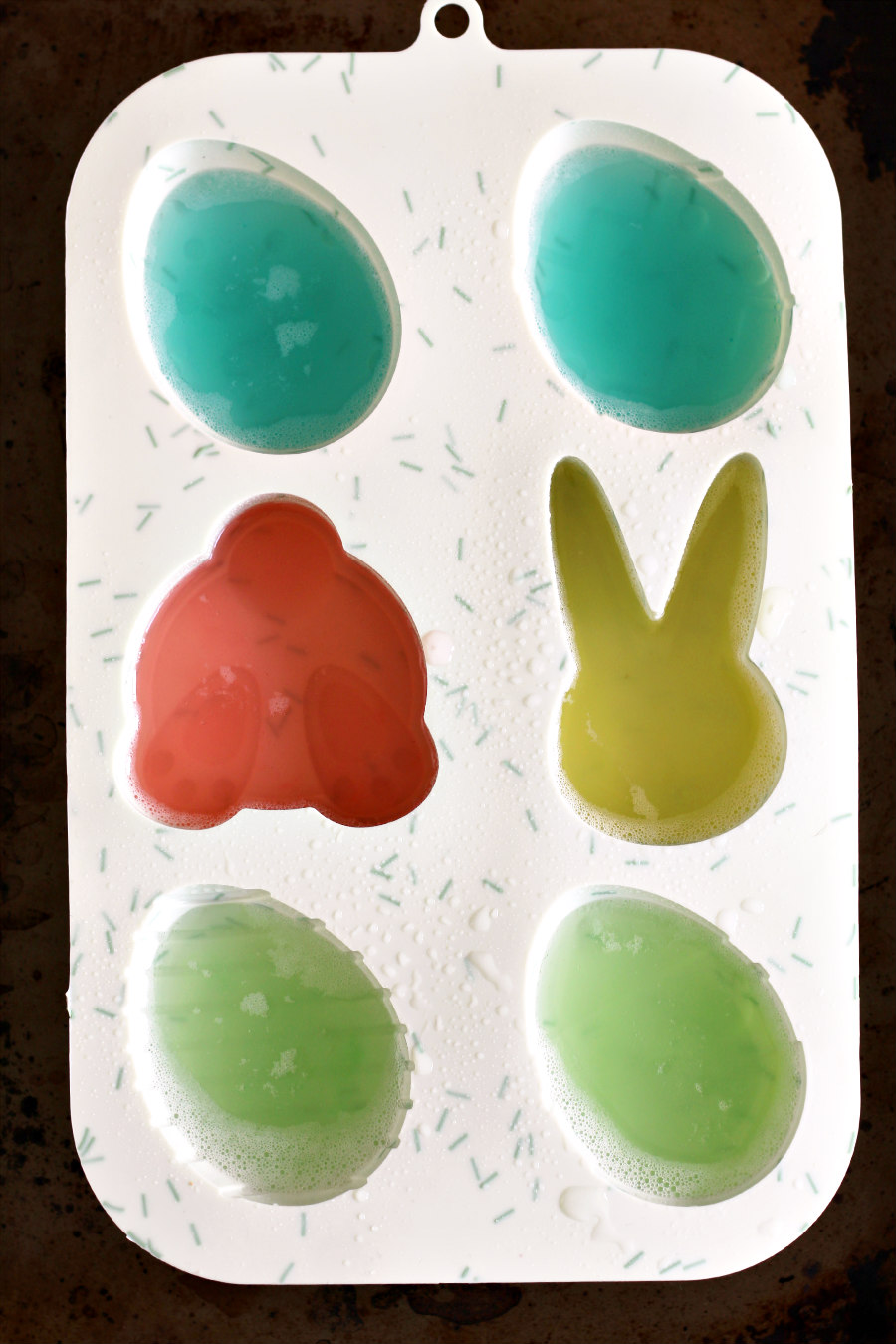 Colorful liquid soap and gelatin poured into a silicone Easter mold. 
