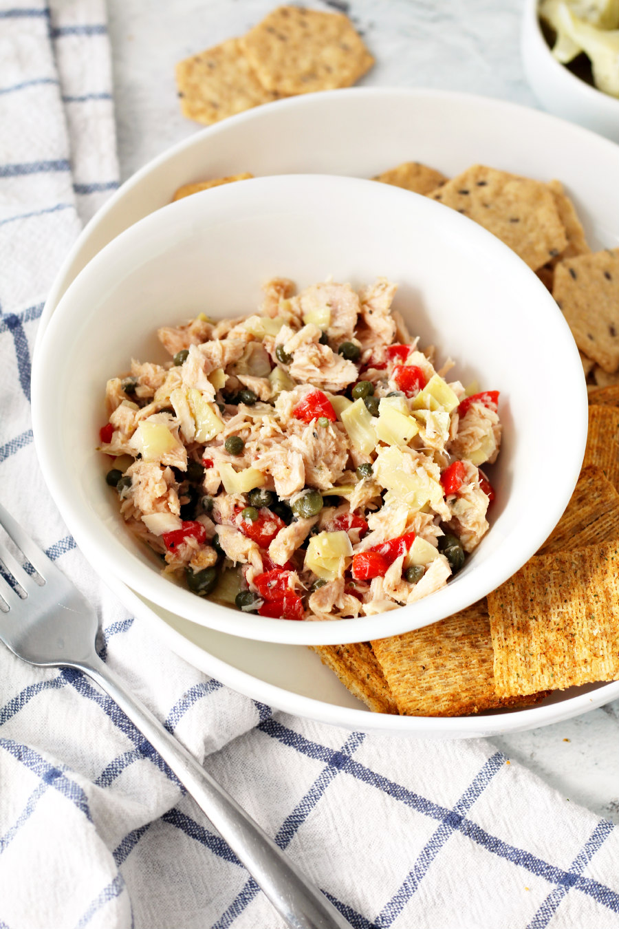 Mediterranean Tuna Salad in a bowl next to Crunchmaster and Triscuit crackers.