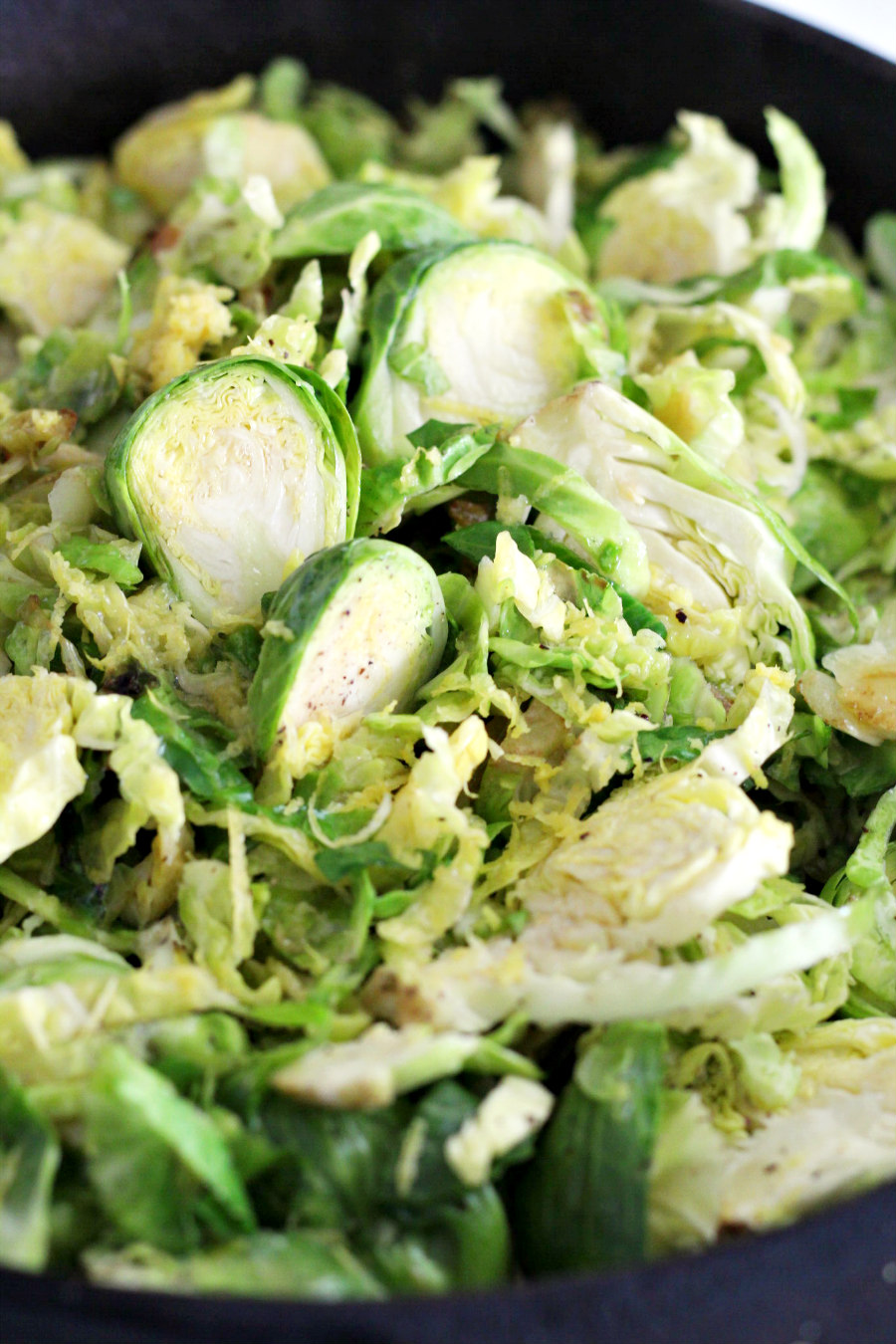 Shaved Brussels sprouts seasoned with salt and pepper in a cast iron skillet. 