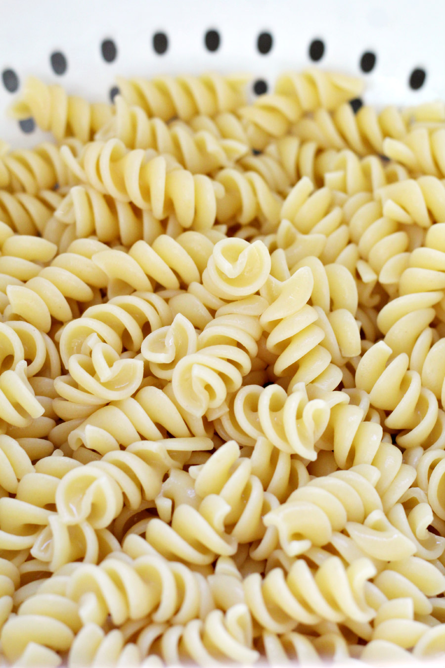 Cooked rotini pasta in a white colander.