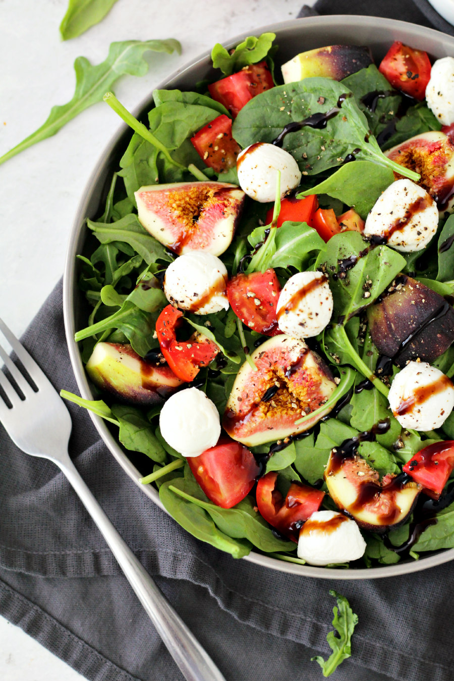 Partial top view of Trader Joe's Inspired Black Fig and Balsamic Salad with fork and baby arugula leaves in photo.