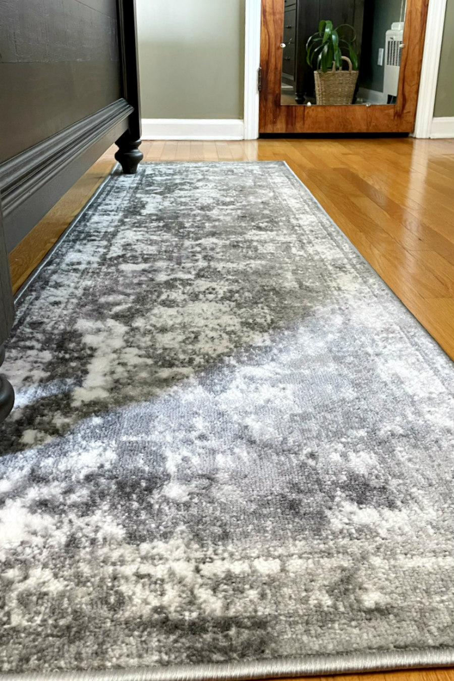 View of gray distressed runner rug in front of bed.