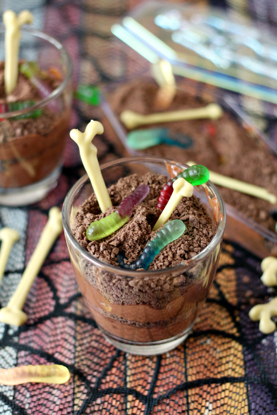 Cups and plastic coffin of Dirt and Worm Chocolate Pudding decorated with gummy worms and plastic bones.