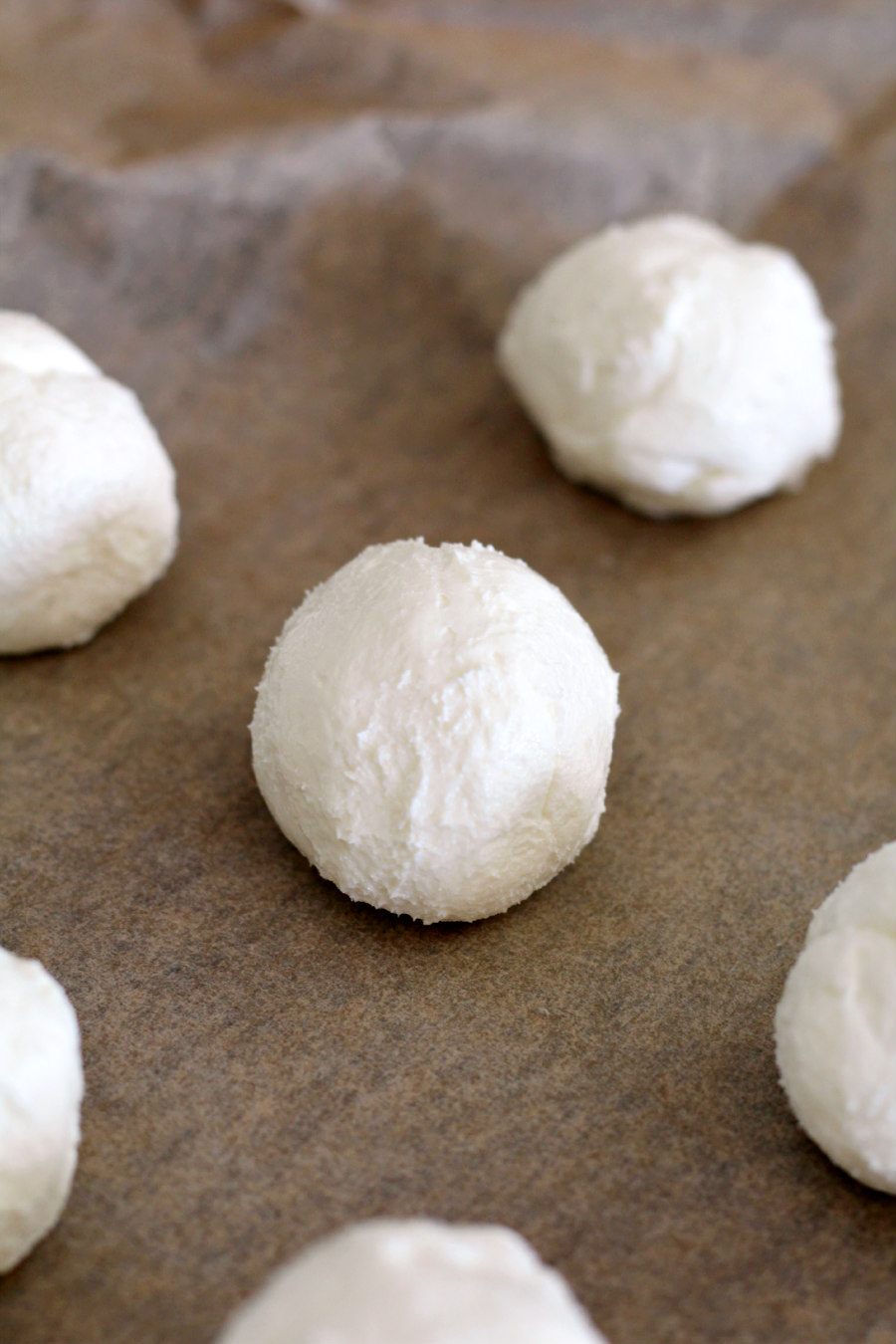 Goat cheese and cream cheese mixture rolled into balls and placed on parchment paper lined baking sheet.